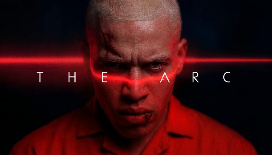A shaven-headed prisoner in orange behind a red line and The Arc title